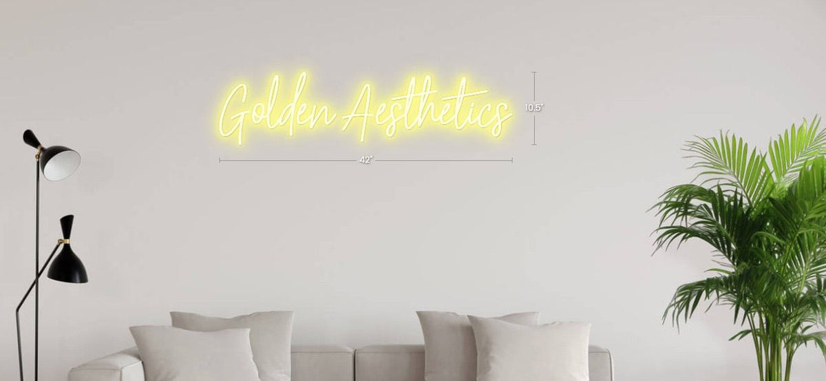 Yellow neon script 'Golden Aesthetics' with measurements above light gray wall, beige sofa, black floor lamp, green.
