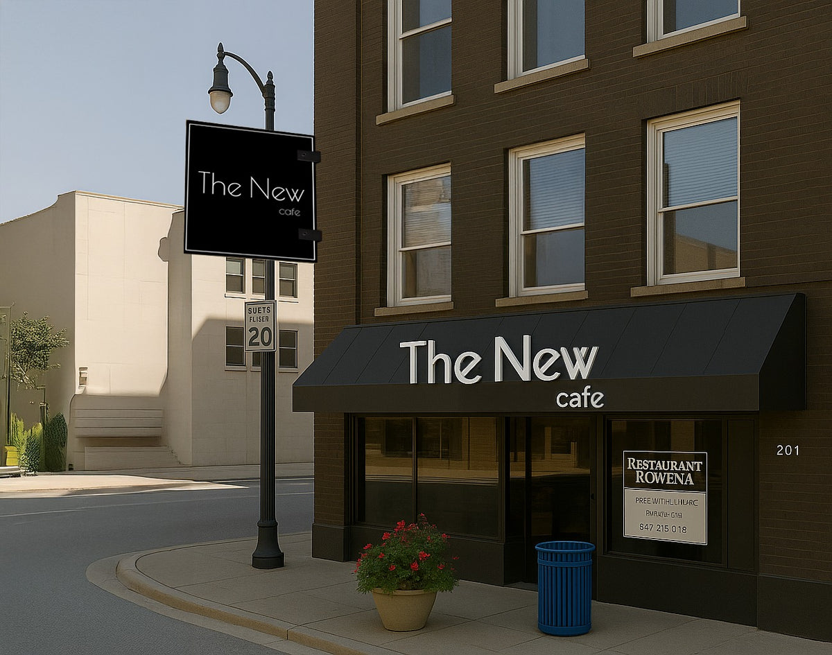 A brown brick building with 'The New' cafe black awning, hanging sign, planter of red flowers and blue trash bin.