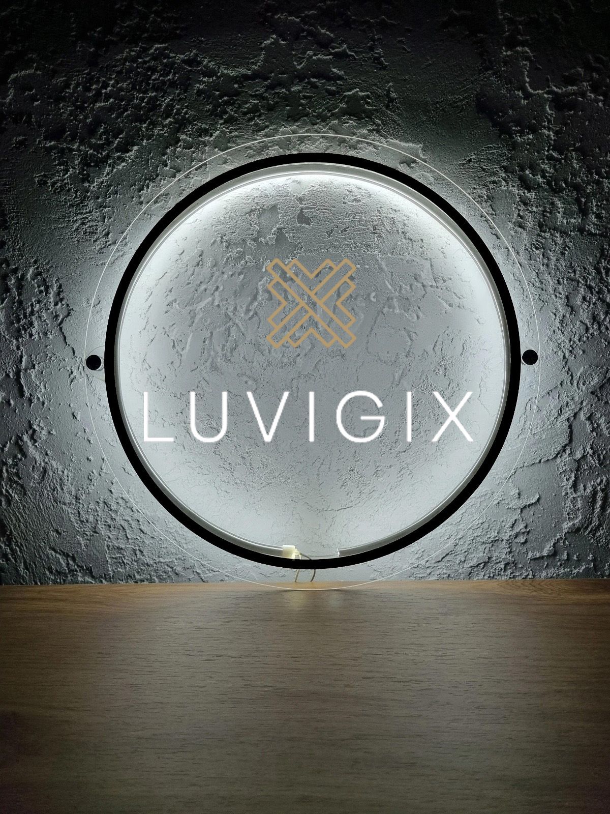 Custom Luvigix round halo backlit acrylic sign by Volt Signs, gold geometric emblem with white wordmark on textured concrete wall, premium brand.