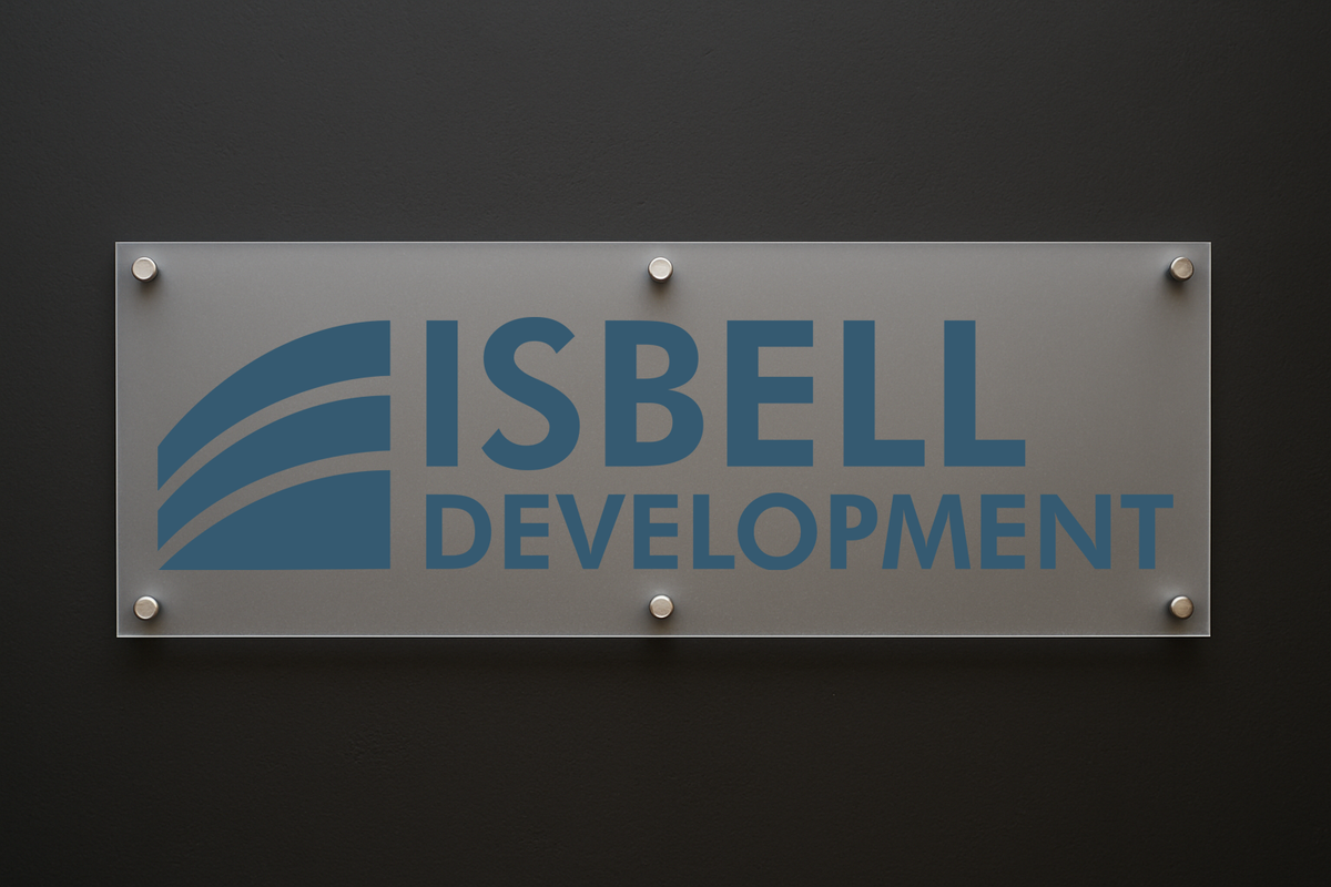 A frosted glass office plaque mounted on a dark wall displays a blue Isbell Development logo and text.