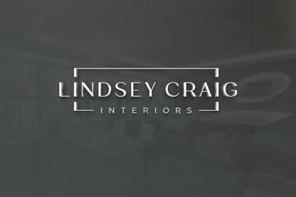 White 3D lettering 'LINDSEY CRAIG' framed by white corner brackets with 'INTERIORS' below on dark gray reflective wall.
