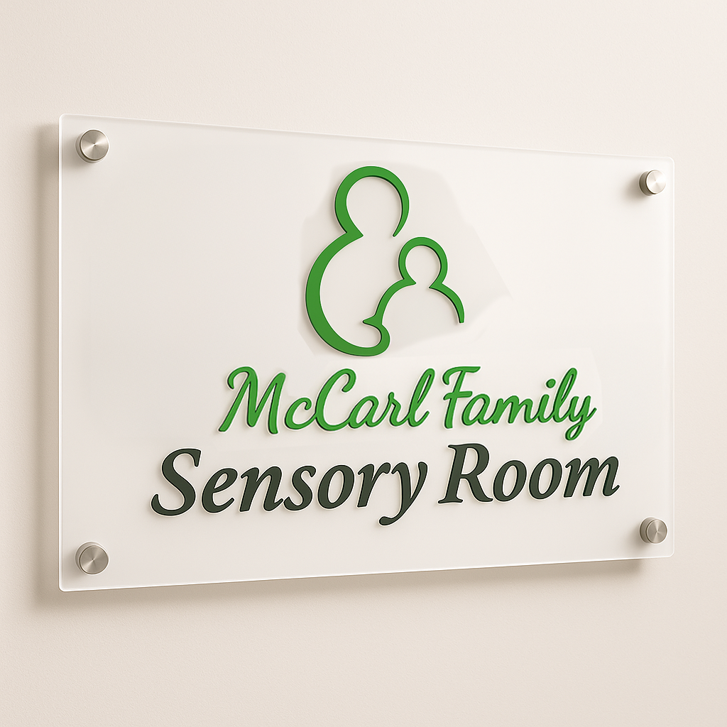 Acrylic wall sign with green parent-and-child logo and script 'McCarl Family' above 'Sensory Room'.