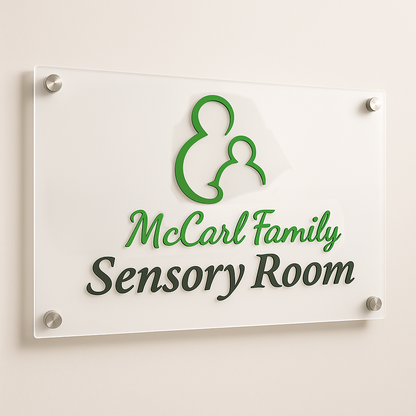 Acrylic wall sign with green parent-and-child logo and script 'McCarl Family' above 'Sensory Room'.
