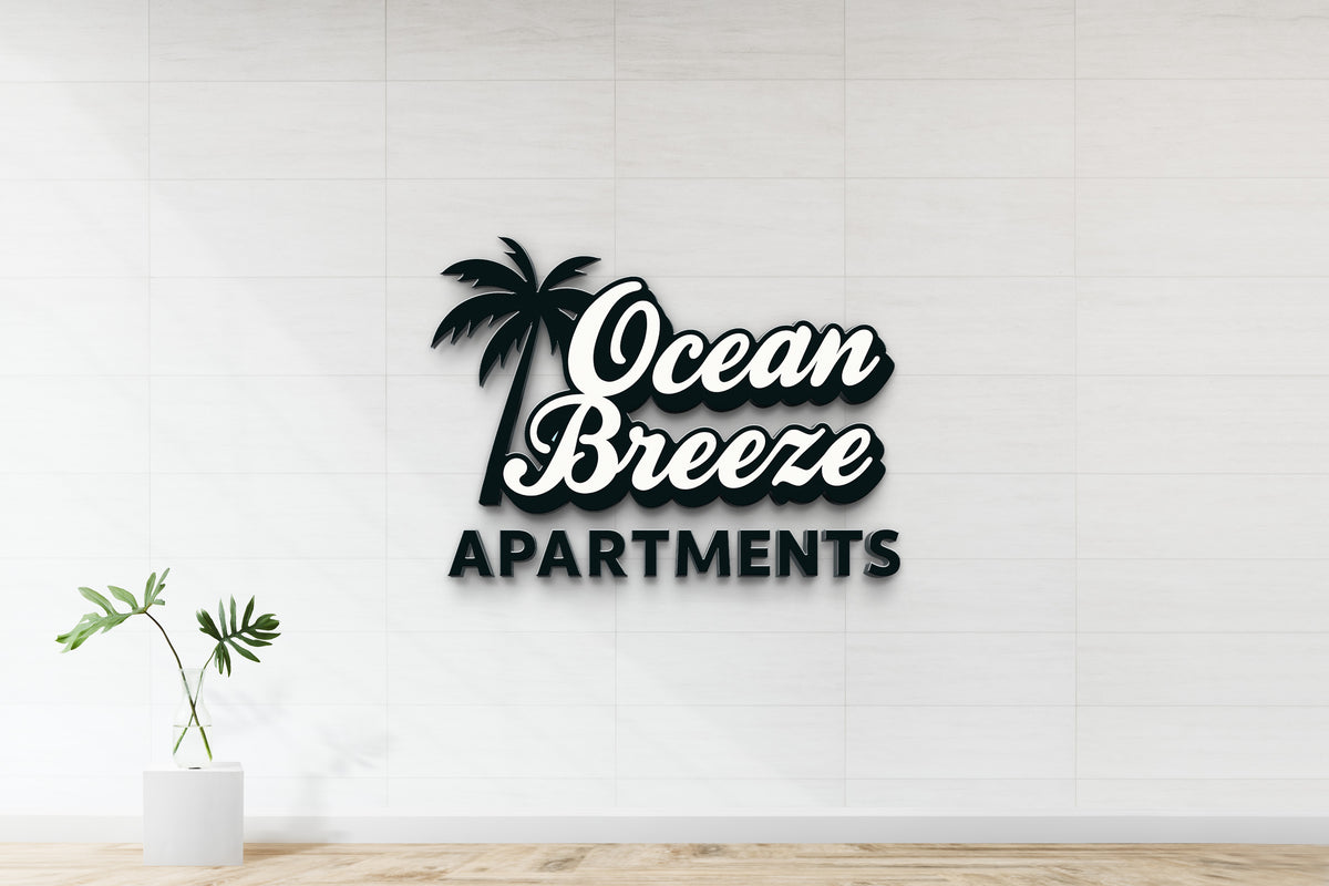 Black and white 'Ocean Breeze Apartments' 3D sign with palm silhouette on white tiled wall, glass vase plant.