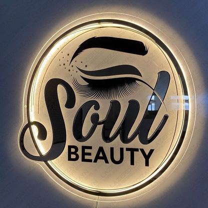 Illuminated circular beauty sign with black eyebrow and long eyelash above script 'Soul' and block 'BEAUTY'.
