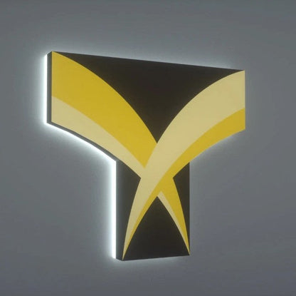 Backlit 3D T-shaped wall sign with black base and yellow curved chevron stripes on a gray wall.