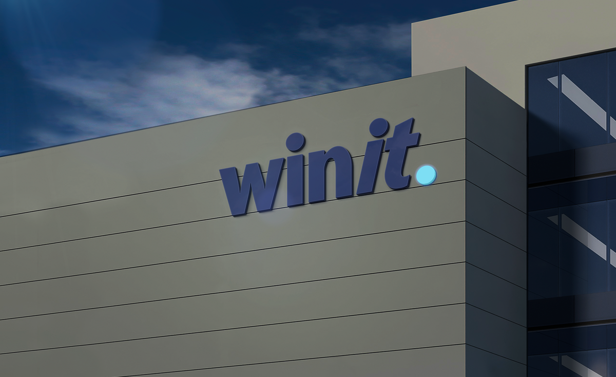 A modern gray building facade with a large navy 'winit' logo and a glowing light-blue dot under a cloudy sky.